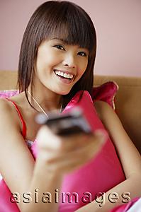 Asia Images Group - Young woman holding TV remote control