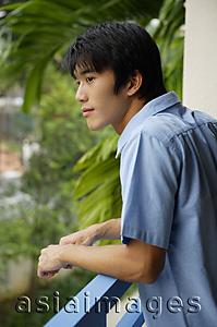 Asia Images Group - Young man leaning on railing, looking away