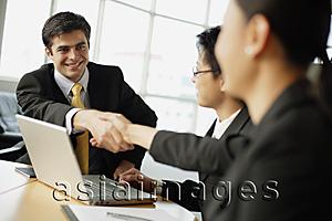 Asia Images Group - Business people shaking hands across table