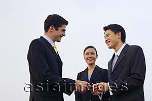 Asia Images Group - Businessmen exchanging business cards, businesswoman in the background