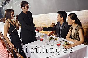 Asia Images Group - Couples sitting in restaurant, men shaking hands