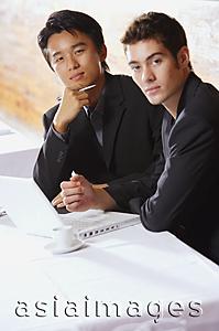 Asia Images Group - Two men sitting in restaurant with laptop, looking at camera