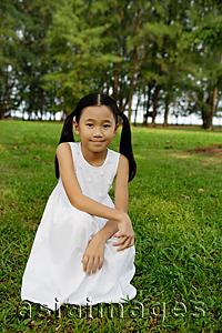 Asia Images Group - Girl in white dress, crouching on grass