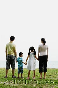 Asia Images Group - Family of four, looking out to sea, rear view