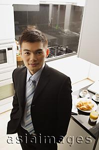 Asia Images Group - Businessman in kitchen, looking up at camera