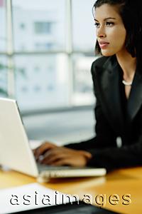 Asia Images Group - Businesswoman dressed in black, using laptop, looking away