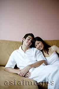 Asia Images Group - Couple lounging on sofa, looking at camera