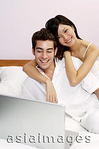 Asia Images Group - Couple on bed, looking at laptop