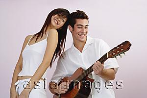 Asia Images Group - Man playing guitar, woman standing next to him smiling