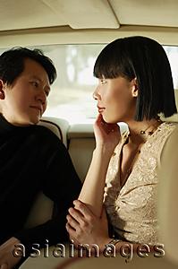 Asia Images Group - Couple sitting in car interior, facing each other, woman with hand on chin
