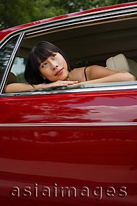 Asia Images Group - Woman in moving car, leaning on door frame, looking away