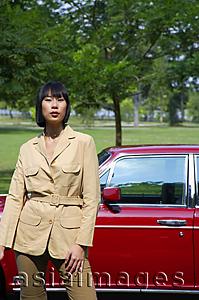 Asia Images Group - Woman in tan jacket standing next to red car
