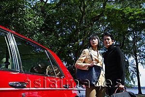 Asia Images Group - Couple carrying bags, standing next to red car