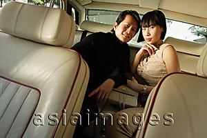 Asia Images Group - Couple sitting in backseat of car, looking at camera