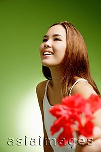 Asia Images Group - Young woman holding Hibiscus flower, focus on the background