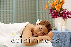Asia Images Group - Young woman in spa, flower in hair, lying on massage table, eyes closed