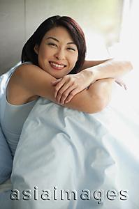 Asia Images Group - Woman on bed hugging knees, arms crossed