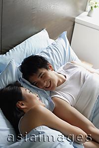 Asia Images Group - Couple lying in bed, smiling at each other