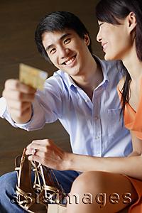 Asia Images Group - Woman holding shoes, man holding credit card towards camera