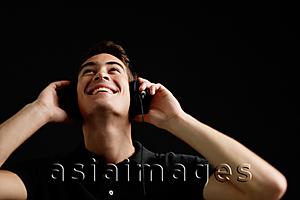 Asia Images Group - Man with headphones, listening to music, looking up