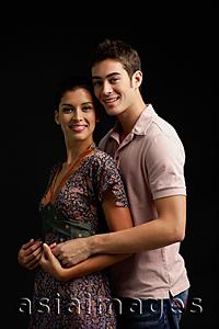 Asia Images Group - Couple in studio, embracing, smiling at camera