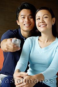 Asia Images Group - Couple sitting side by side, man holding TV remote control
