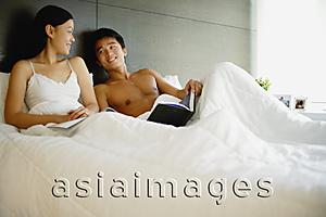 Asia Images Group - Couple in bed, with book and magazine
