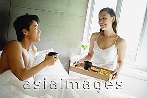 Asia Images Group - Woman holding breakfast tray, man sitting in bed
