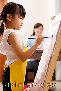 Asia Images Group - Girl painting on easel, mother in the background