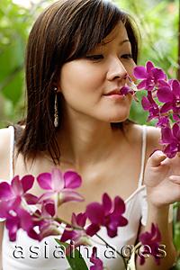 Asia Images Group - Young woman smelling orchids
