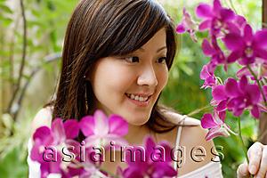 Asia Images Group - Young woman looking at orchids