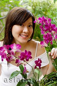 Asia Images Group - Young woman with orchid plant, smiling at camera