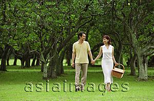 Asia Images Group - Couple walking in park, woman carrying picnic basket
