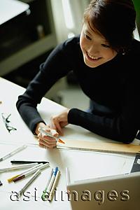 Asia Images Group - Female designer sitting at table with ruler and felt tip marker