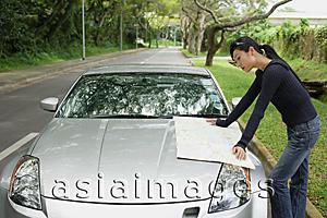 Asia Images Group - Woman leaning on car, looking at map