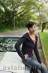 Asia Images Group - Woman sitting on hood of car, map next to her