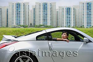 Asia Images Group - Woman in front seat of silver sports car, looking out the window