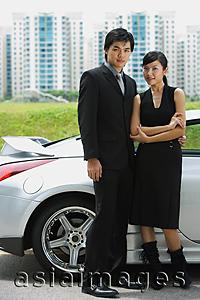 Asia Images Group - Couple standing side by side, silver sports car behind them