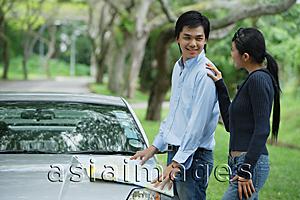 Asia Images Group - Couple next to car, man turning to look at woman