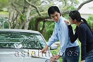 Asia Images Group - Couple looking a map on hood of car, woman with hand on man's shoulder
