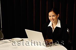 Asia Images Group - Businesswoman sitting in restaurant using laptop, smiling
