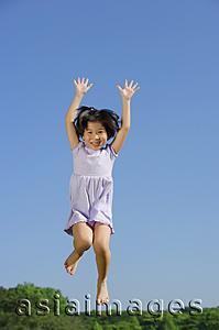 Asia Images Group - Girl jumping in mid air, arms outstretched, smiling