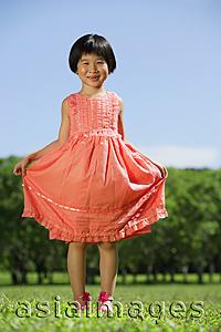 Asia Images Group - Girl in peach dress, standing in park