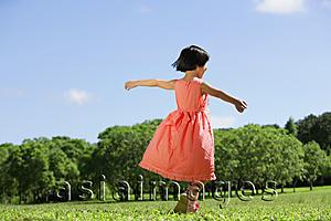 Asia Images Group - Girl in peach dress, walking on grass, arms outstretched