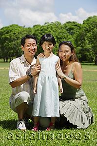 Asia Images Group - Father and mother crouching on either side of daughter, portrait