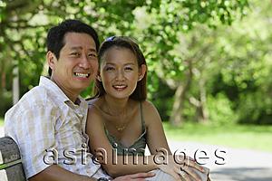 Asia Images Group - Couple sitting on bench, looking at camera