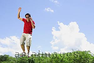 Asia Images Group - Man jumping in mid air, holding mobile phone