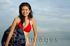 Asia Images Group - Young woman holding skimboard, portrait