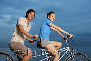 Asia Images Group - Couple on tandem bicycle, smiling at camera