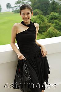Asia Images Group - Young woman in black dress, leaning on ledge